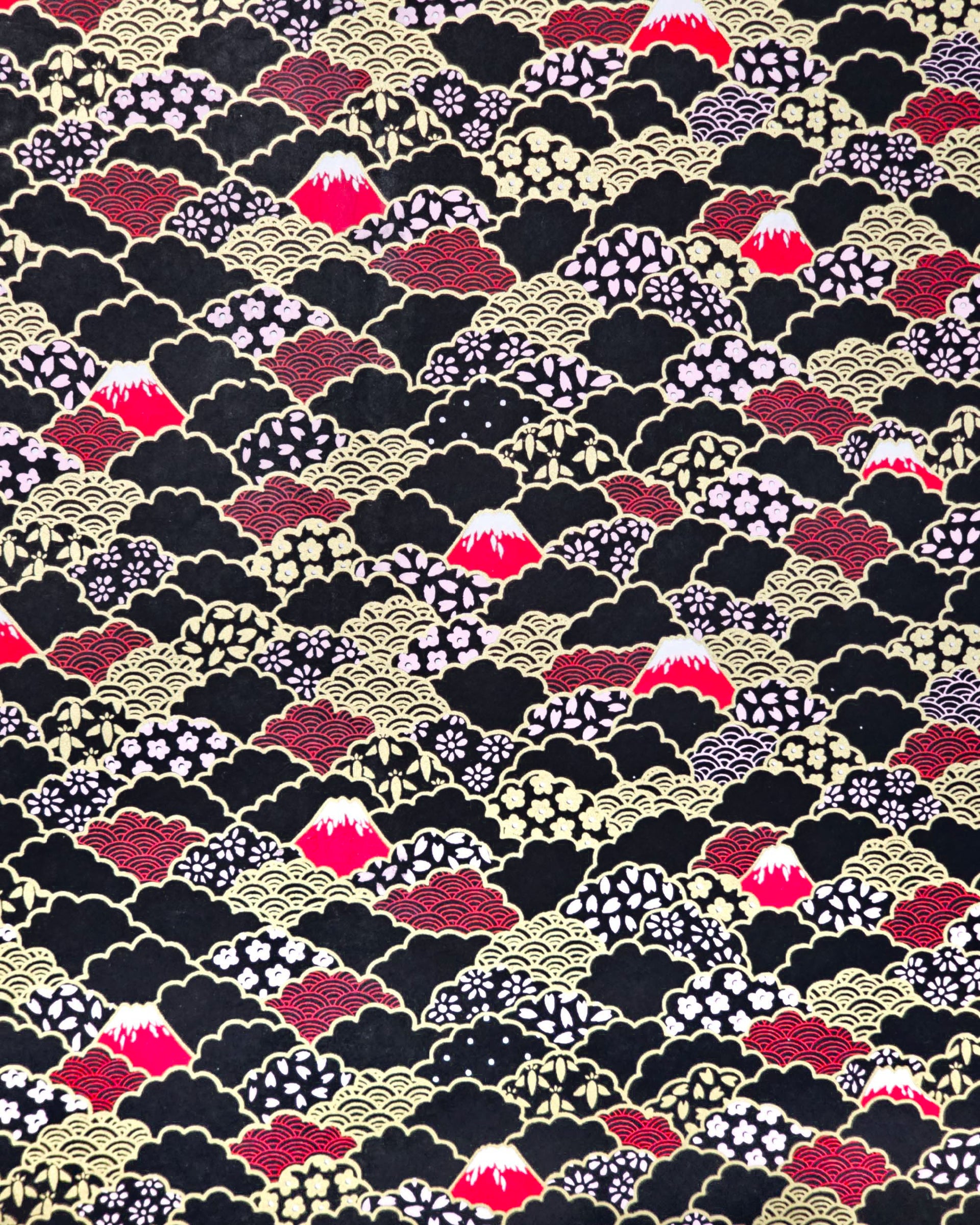 Japanese chiyogami paper featuring red Mt Fuji and gold clouds filled with assorted gold and pink geometric and flower designs on a black background.