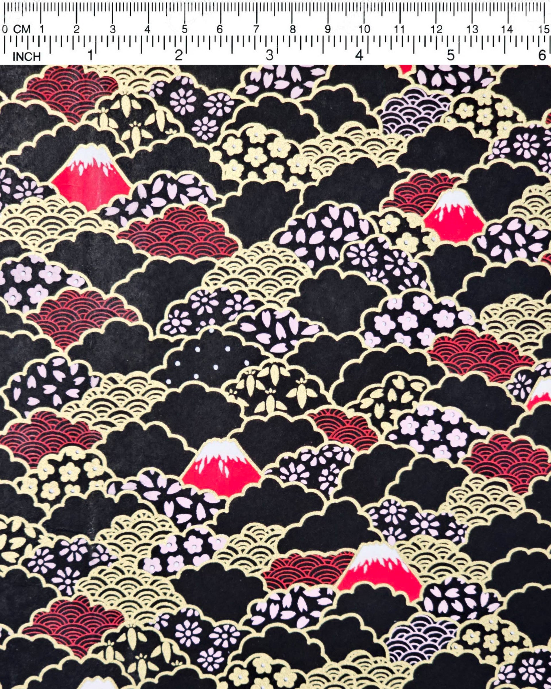Japanese chiyogami paper featuring red Mt Fuji and gold clouds filled with assorted gold and pink geometric and flower designs on a black background.