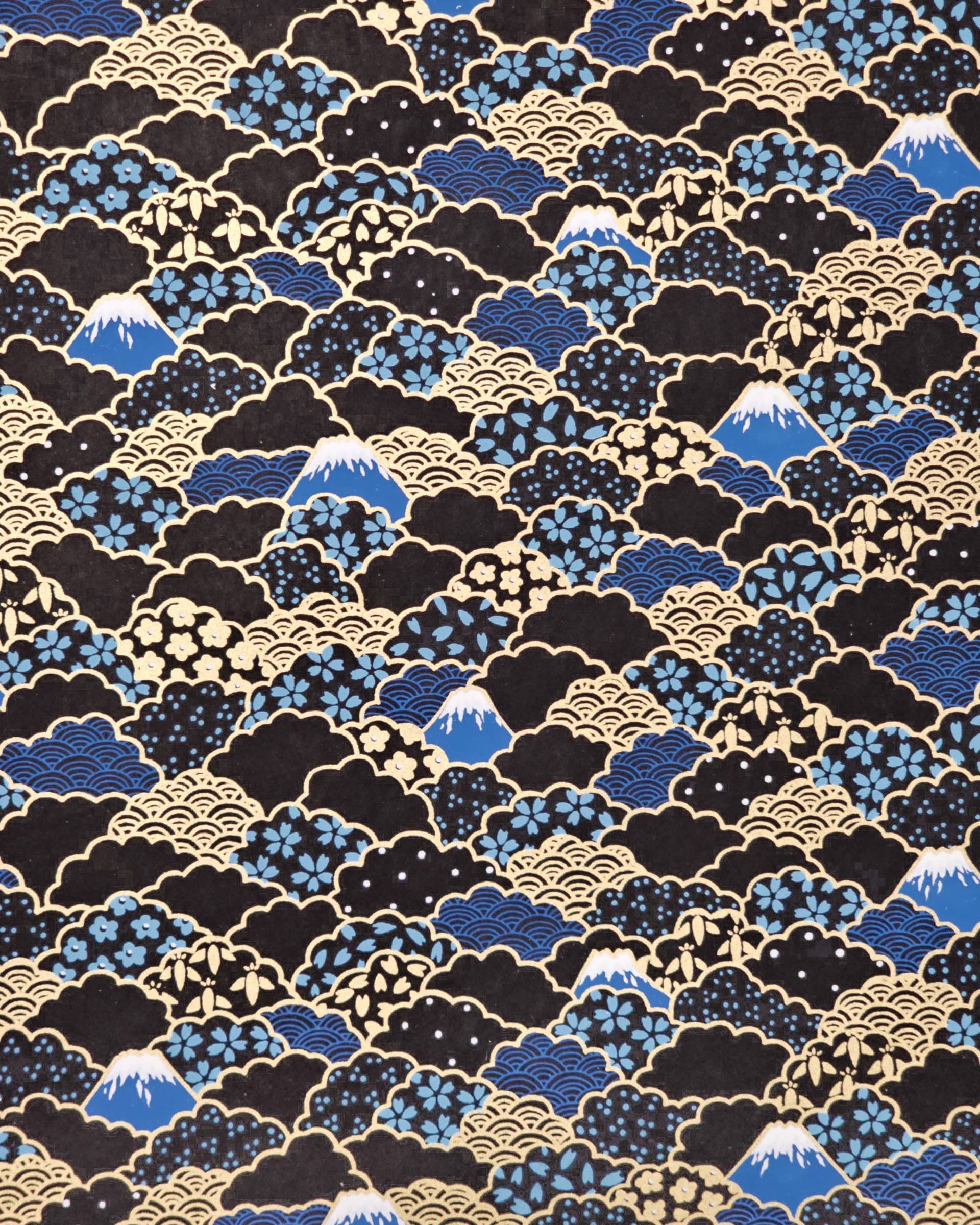 Japanese chiyogami paper featuring blue Mt Fuji and gold clouds filled with assorted gold and blue geometric and flower designs on a black background.