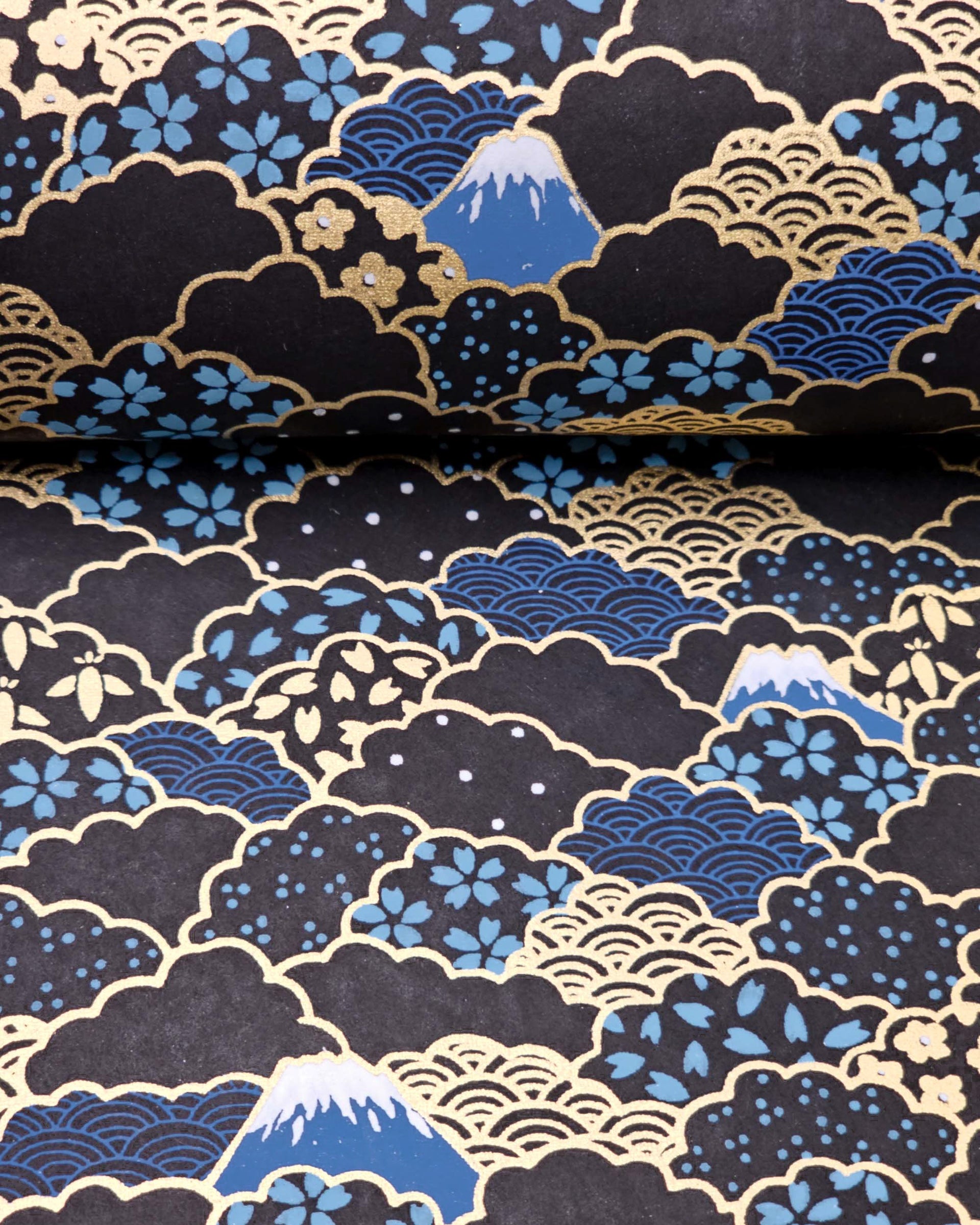 Japanese chiyogami paper featuring blue Mt Fuji and gold clouds filled with assorted gold and blue geometric and flower designs on a black background.