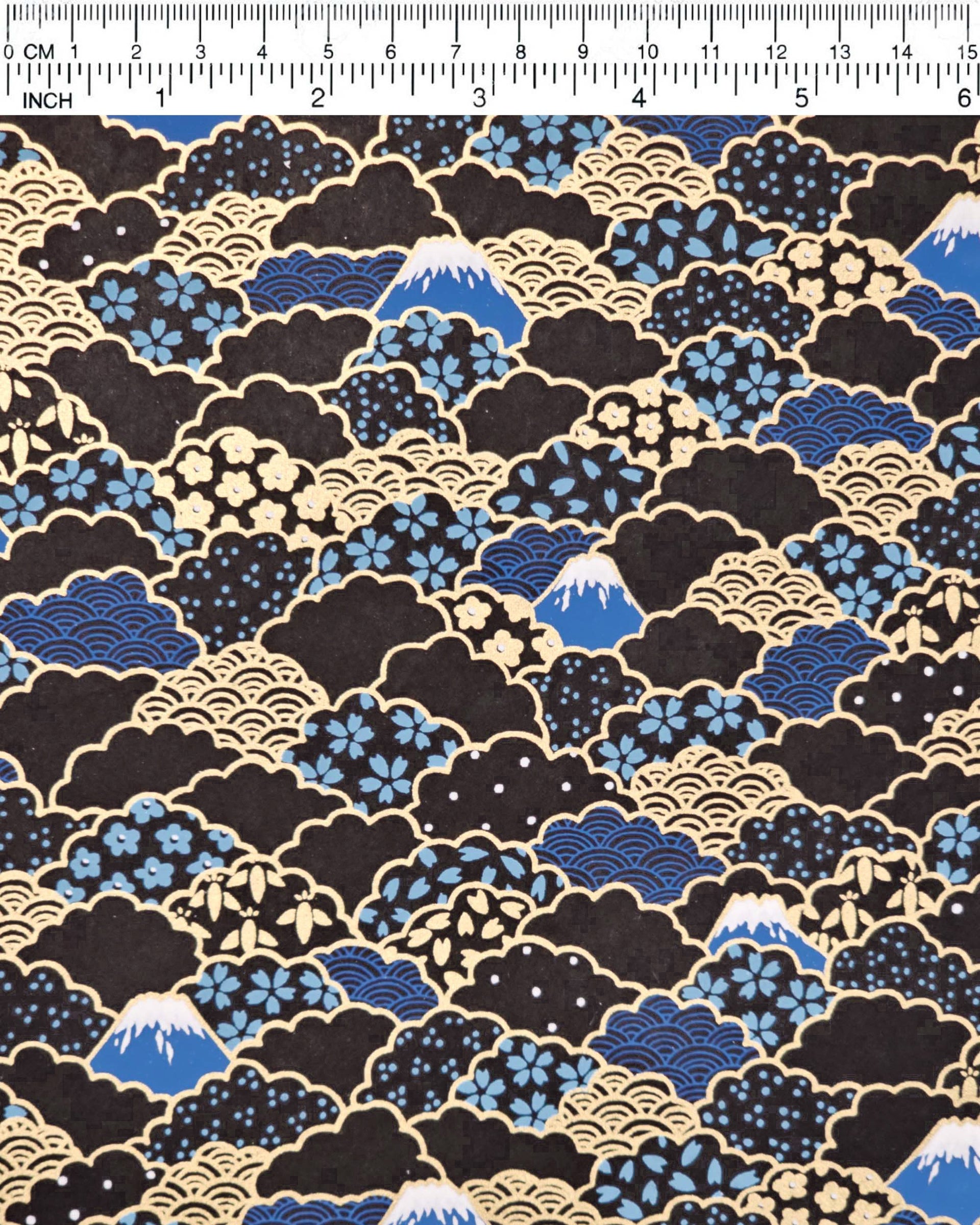 Japanese chiyogami paper featuring blue Mt Fuji and gold clouds filled with assorted gold and blue geometric and flower designs on a black background.