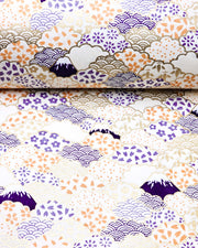 Japanese chiyogami paper featuring dark blue Mt Fuji and gold clouds filled with assorted gold, orange, and purple geometric and flower designs on a white background.