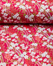 Japanese chiyogami paper featuring pink and purple plum blossoms and pink, green, and purple wisteria on a red background with metallic gold details.