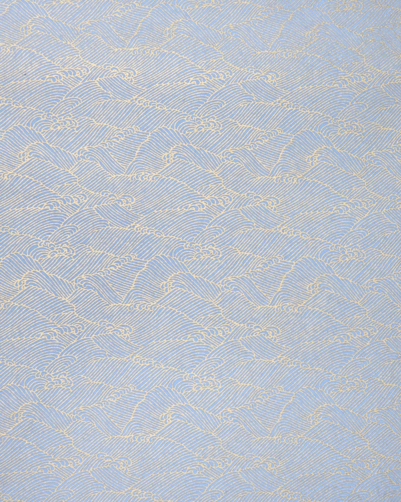 Japanese chiyogami paper featuring small metallic gold waves (aranami) on a light blue background. 