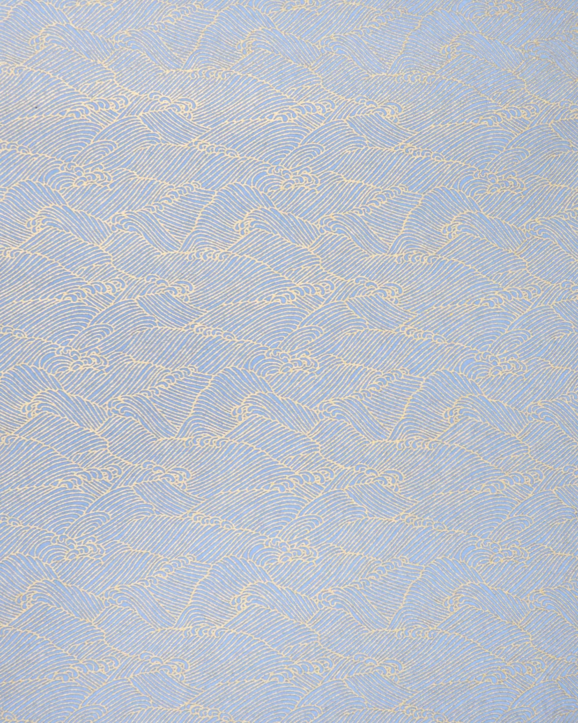 Japanese chiyogami paper featuring small metallic gold waves (aranami) on a light blue background. 