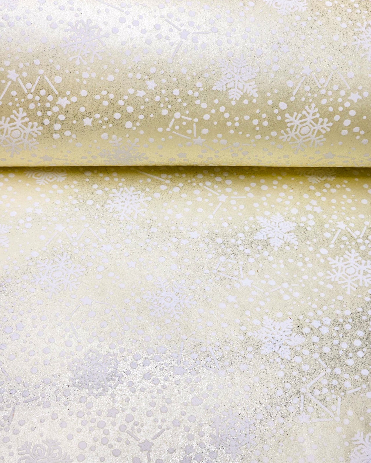 Japanese chiyogami paper featuring assorted white snowflakes and star constellations on a pearlescent light yellow background with metallic silver glitter details.