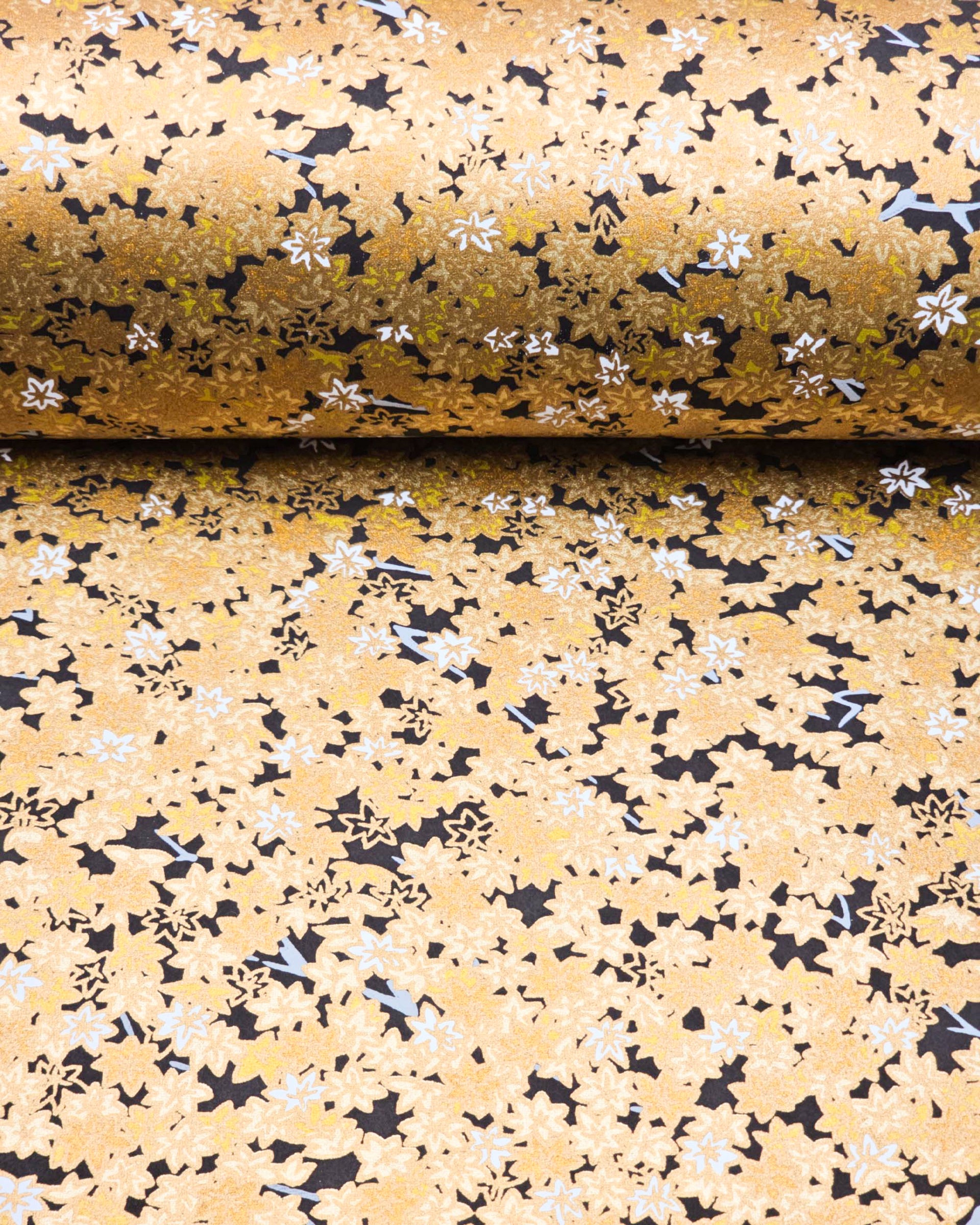 Japanese chiyogami paper featuring small gold and white momiji (maple leaves) on a black background with metallic gold details.
