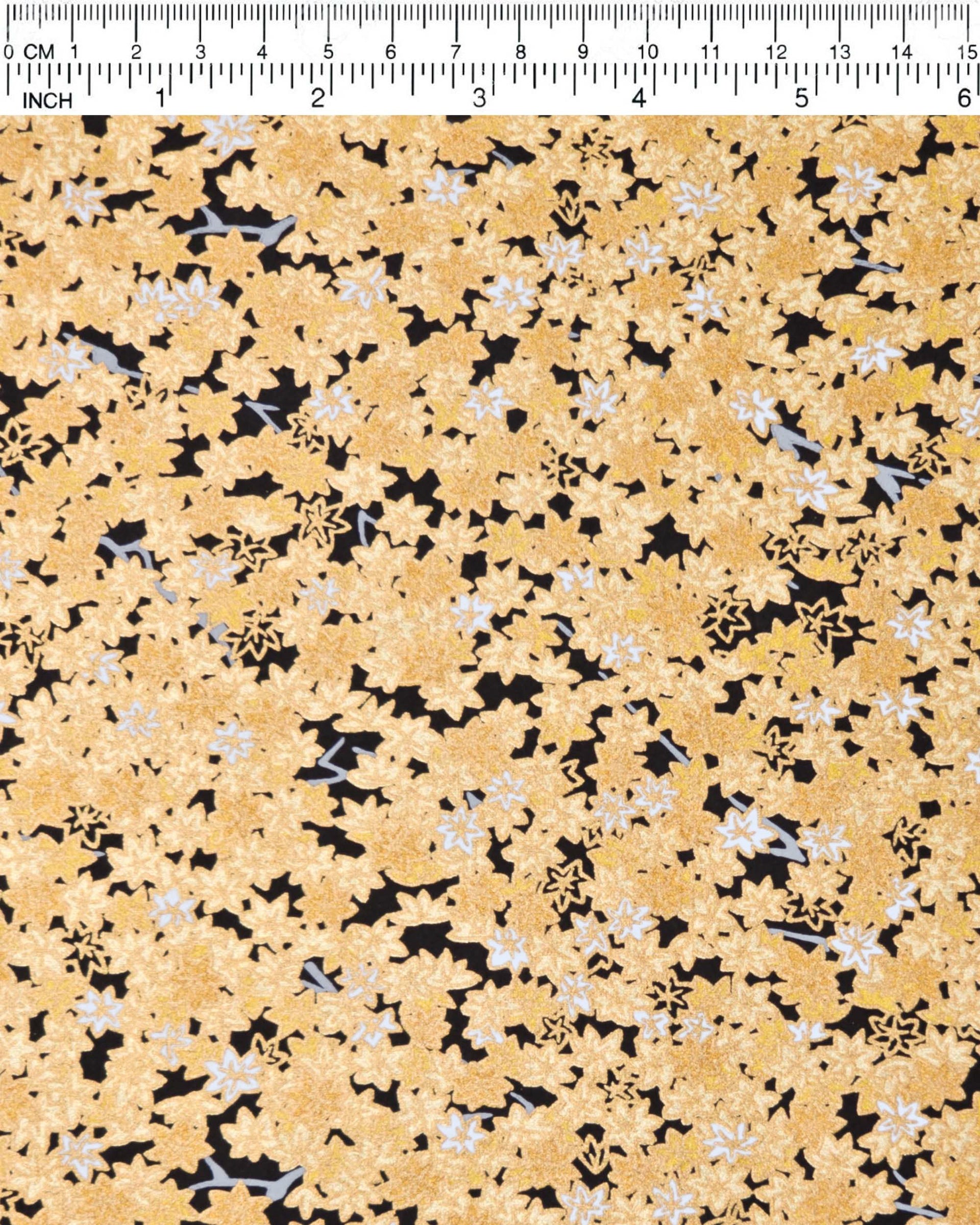 Japanese chiyogami paper featuring small gold and white momiji (maple leaves) on a black background with metallic gold details.