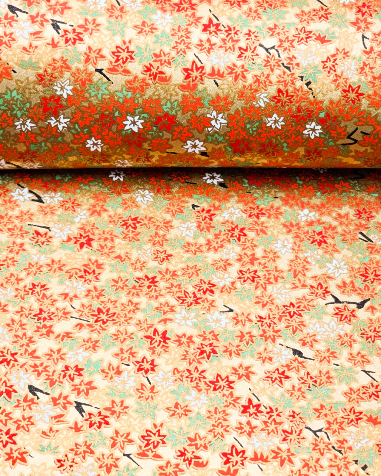 Japanese chiyogami paper featuring small red, green, and white momiji (maple leaves) on a gold background with metallic gold details.