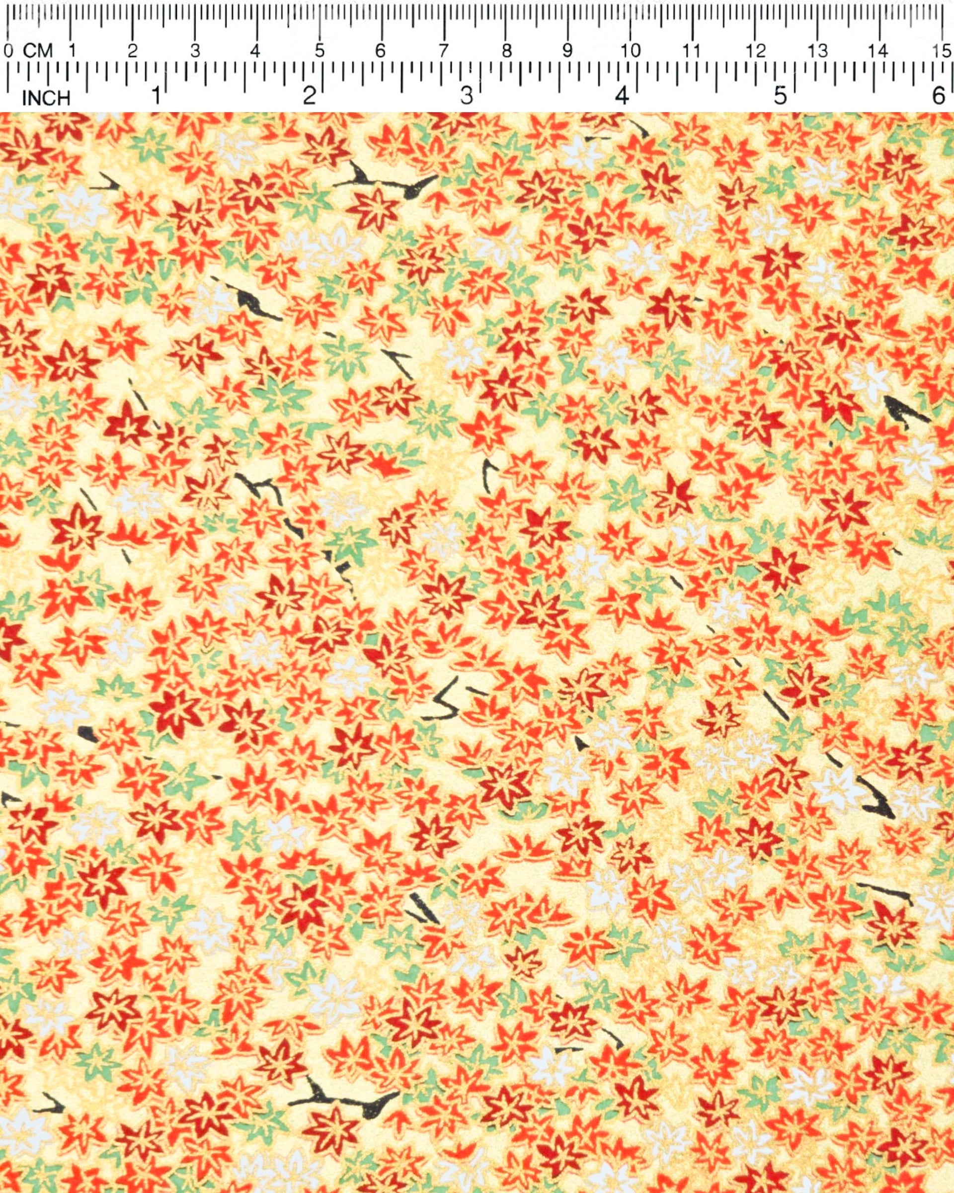 Japanese chiyogami paper featuring small red, green, and white momiji (maple leaves) on a gold background with metallic gold details.