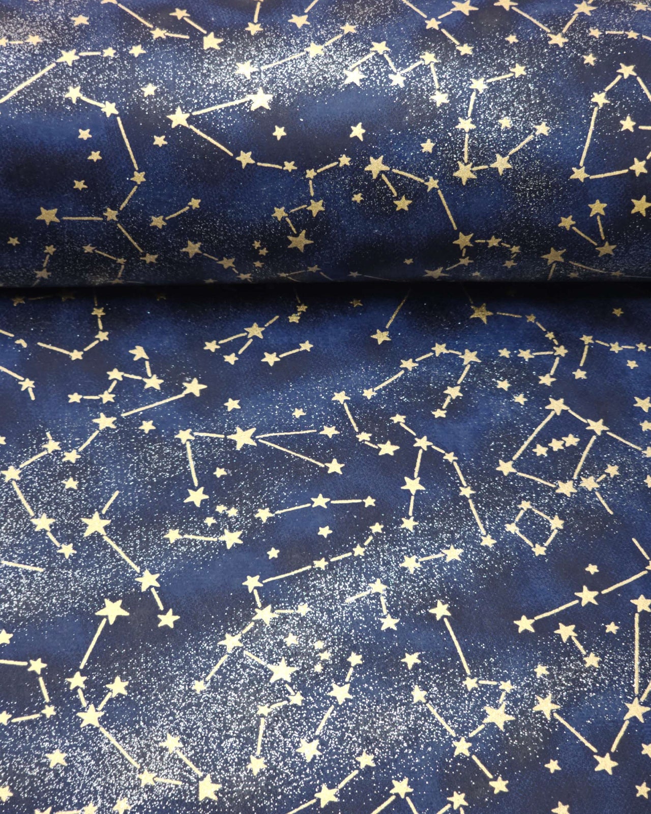Japanese chiyogami paper featuring metallic gold stars and constellations scattered across a dark blue gradient background with shimmering metallic silver stardust.
