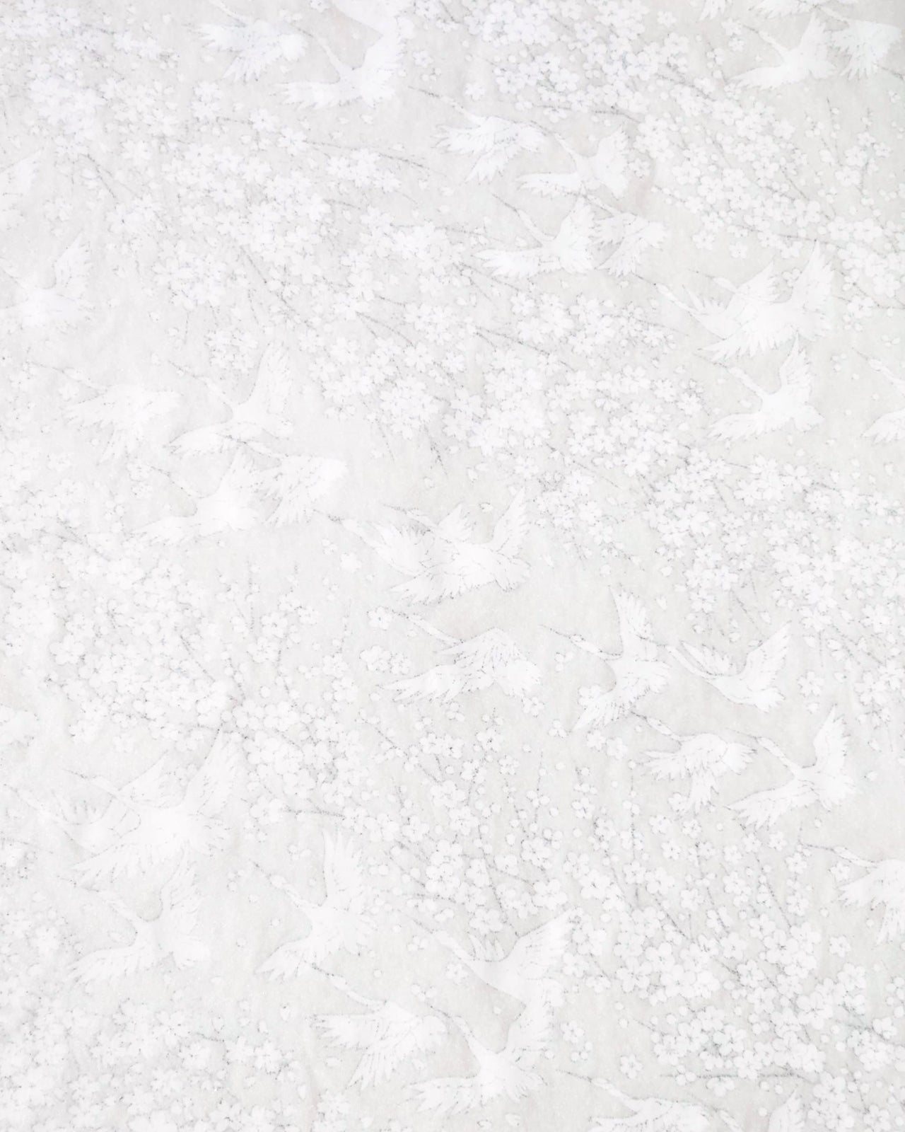 Japanese chiyogami paper featuring white flying cranes and plum and cherry blossoms on a pearlescent white background with metallic silver accents that create a fine glitter-like effect.