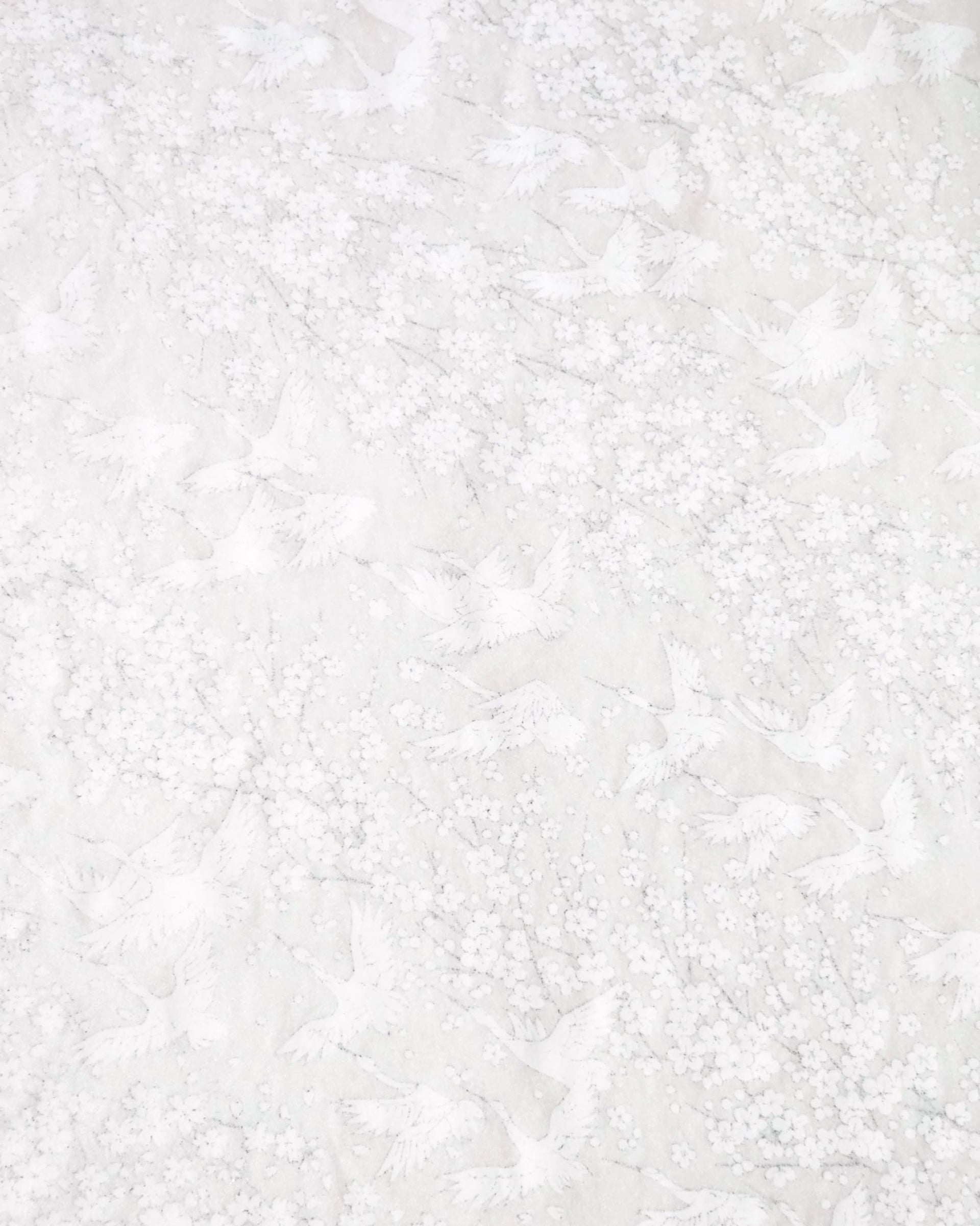 Japanese chiyogami paper featuring white flying cranes and plum and cherry blossoms on a pearlescent white background with metallic silver accents that create a fine glitter-like effect.