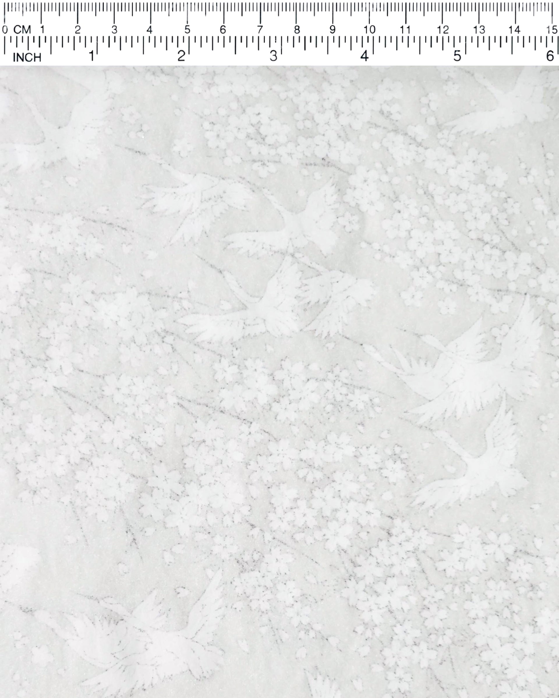 Japanese chiyogami paper featuring white flying cranes and plum and cherry blossoms on a pearlescent white background with metallic silver accents that create a fine glitter-like effect.