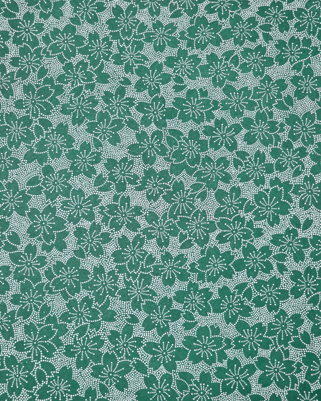 Japanese chiyogami paper featuring white pointillistic cherry blossoms on a dark green background.