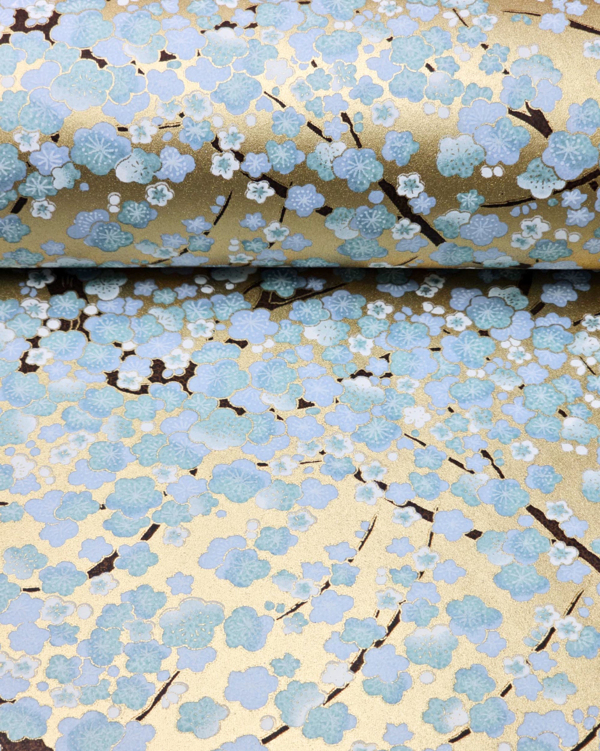 Japanese chiyogami paper featuring light blue and white plum blossom trees with dark brown branches on a gold background with metallic gold details.