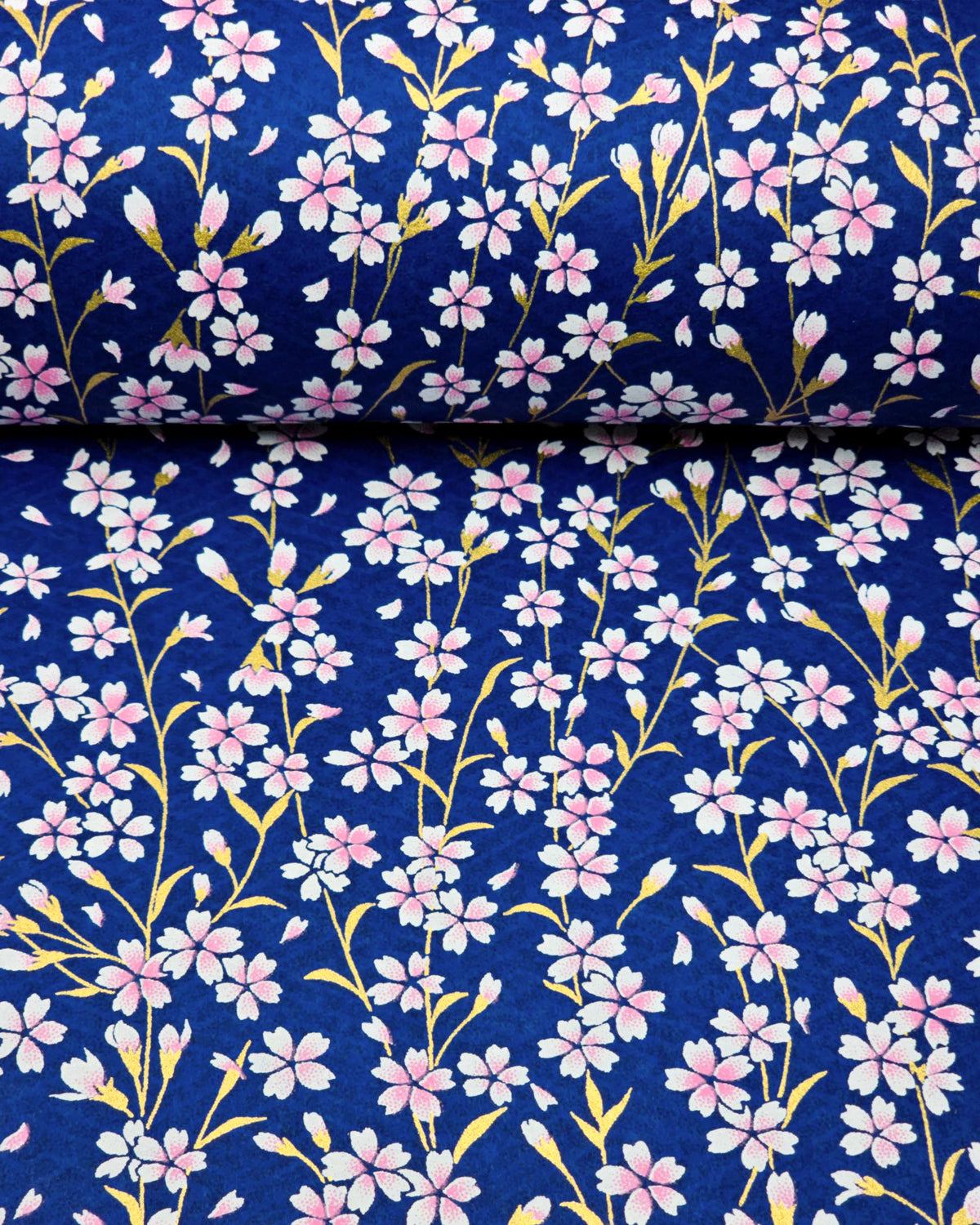 Japanese chiyogami paper featuring pink and white cherry blossoms with metallic gold stems and leaves on a dark blue background, shown rolled to highlight the design.