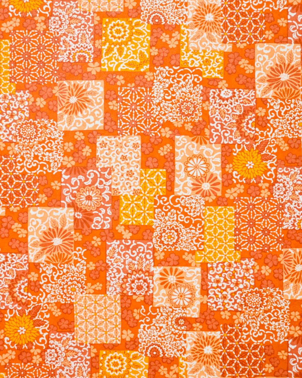 Japanese chiyogami paper featuring a patchwork-style arrangement of assorted floral and traditional Japanese patterns in various shades of orange and white. 