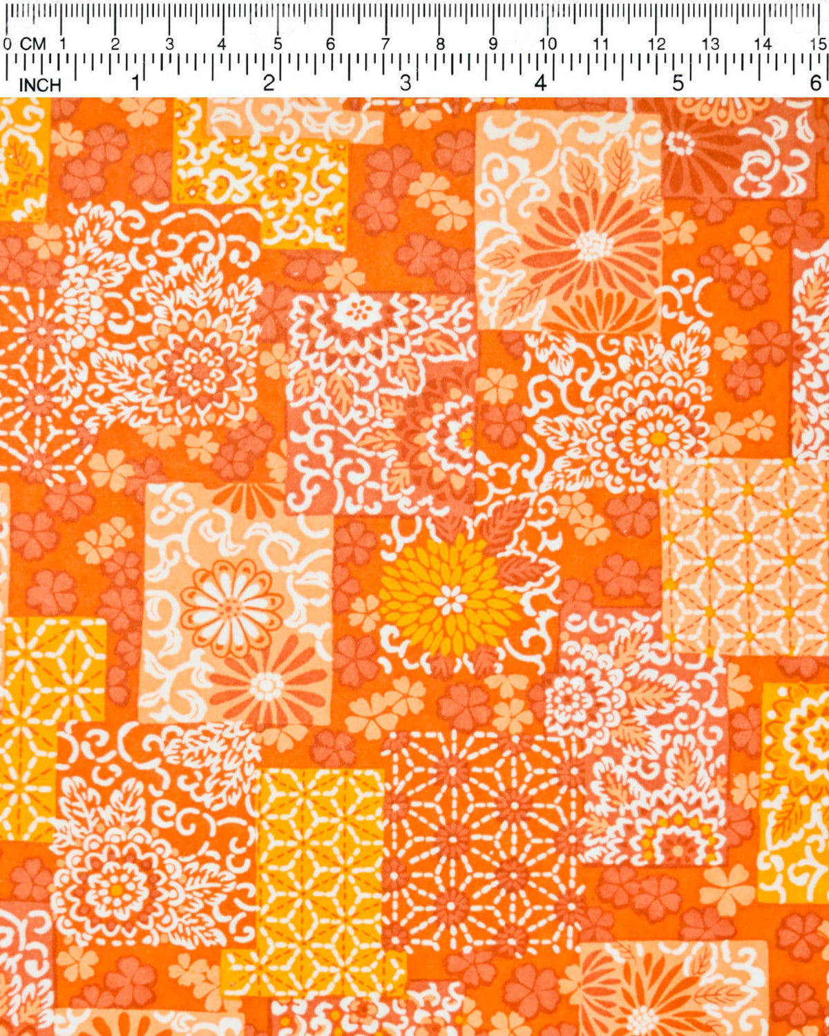 Japanese chiyogami paper featuring a patchwork-style arrangement of assorted floral and traditional Japanese patterns in various shades of orange and white, shown next to a ruler for size reference.
