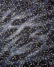 Japanese chiyogami paper featuring metallic gold stars and constellations scattered across a black background with shimmering metallic silver stardust. 