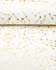 Japanese chiyogami paper featuring metallic gold stars and constellations scattered across a white background with shimmering metallic silver stardust, shown rolled to highlight the design.