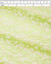 Japanese chiyogami paper featuring small white plum blossom with pink centers and gold matsuba (pine needles) on a green gradient background with metallic gold details, shown next to a ruler for size reference.