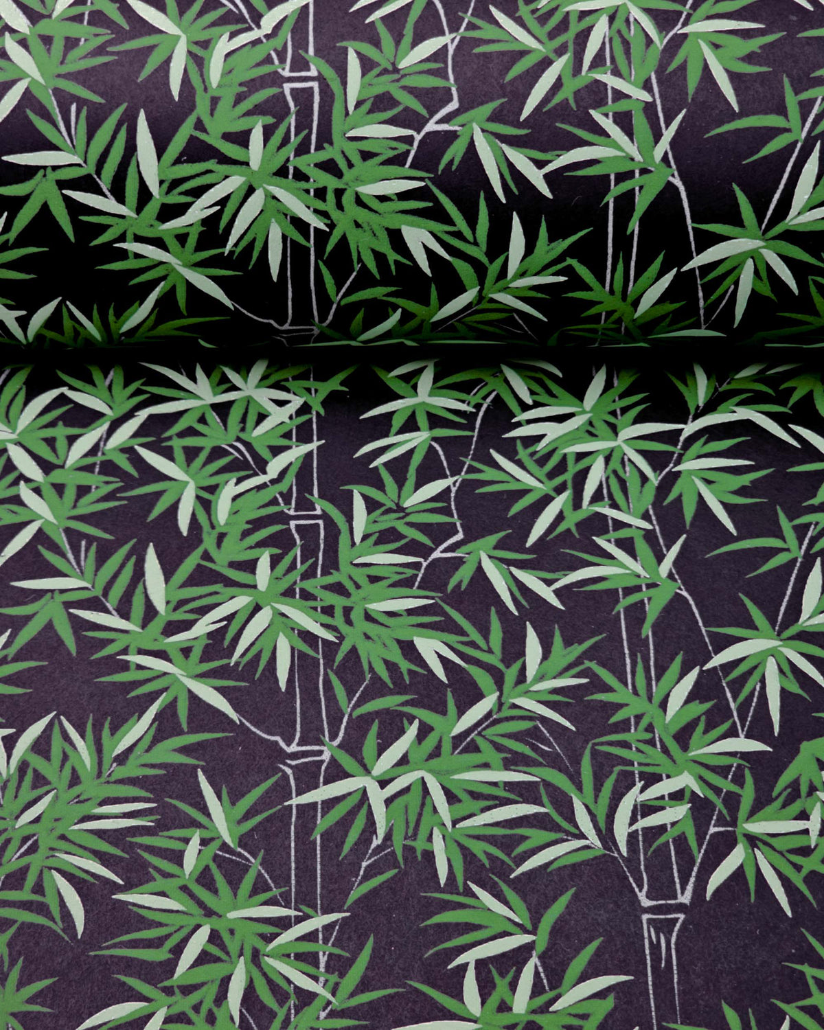 Japanese chiyogami paper featuring bamboo stalks outlined in gray with dark and light green bamboo leaves on a black background, shown rolled to highlight the design.