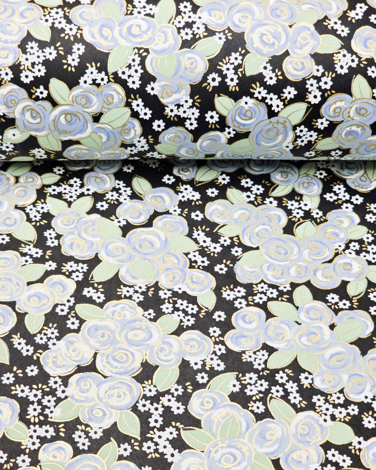 Japanese chiyogami paper featuring blue and white roses with light green leaves and smaller white flowers on a black background with metallic gold details, shown rolled to highlight the design.