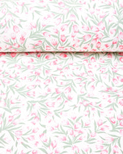 Japanese chiyogami paper featuring pink and white tulips with light green leaves on a white background, shown rolled to highlight the design.