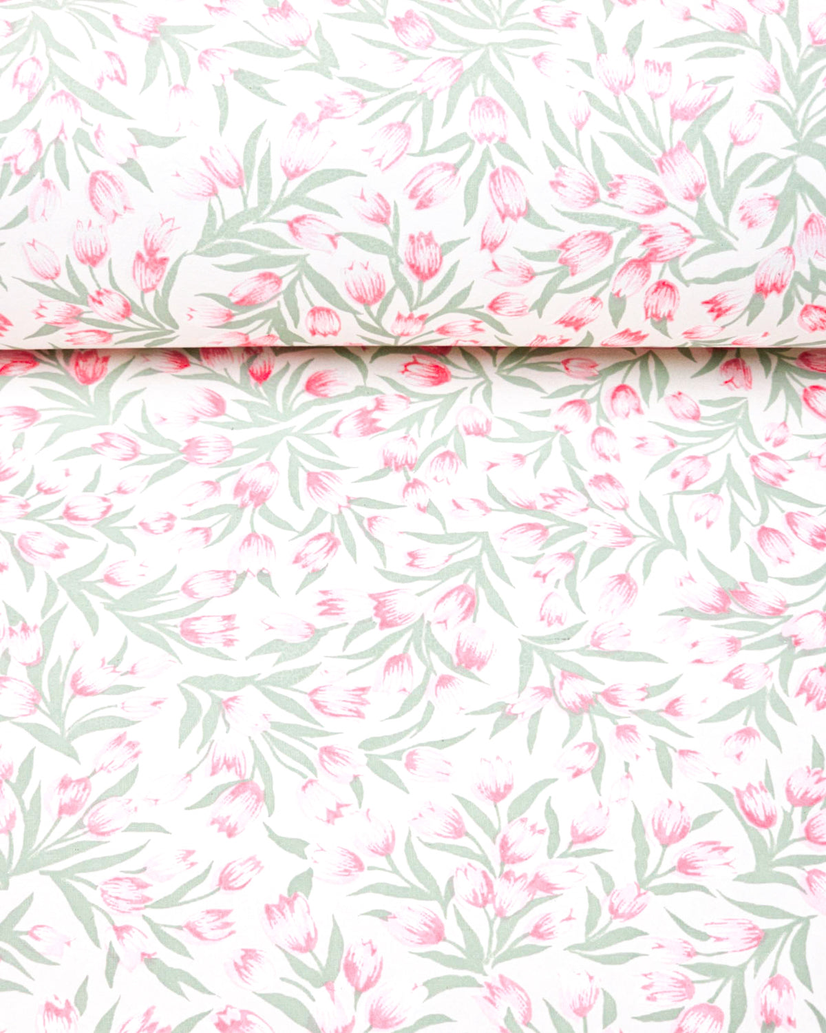 Japanese chiyogami paper featuring pink and white tulips with light green leaves on a white background, shown rolled to highlight the design.