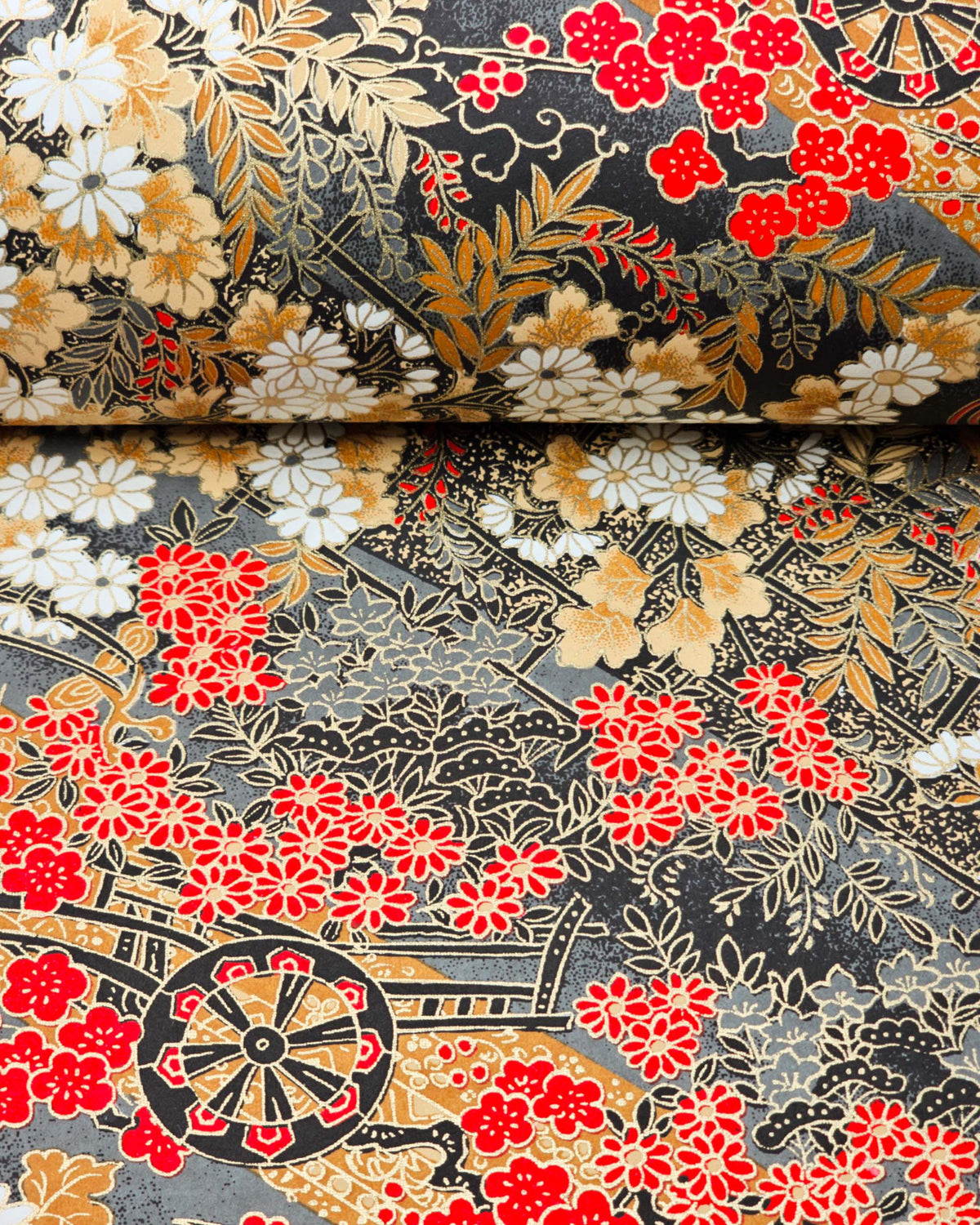 Japanese chiyogami paper featuring black flower carts with assorted red, white, and gray flowers with brown leaves on a gray background with metallic gold details, shown rolled to highlight the design.
