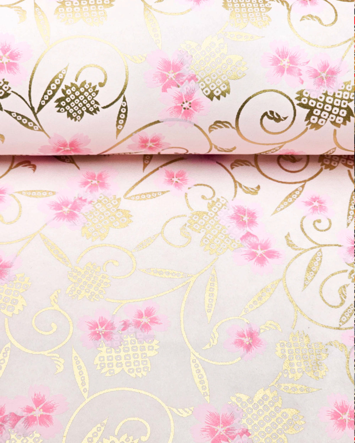 Japanese chiyogami paper featuring pink cherry blossoms alongside gold cherry blossoms and leaves decorated with a traditional kanoko (fawn) pattern on a light pink background, shown rolled to highlight the design.