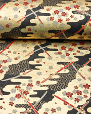 Japanese chiyogami paper featuring red and gray katana swords with gray and maroon red cherry blossoms on a black and gold background with metallic gold details, shown rolled to highlight the design.