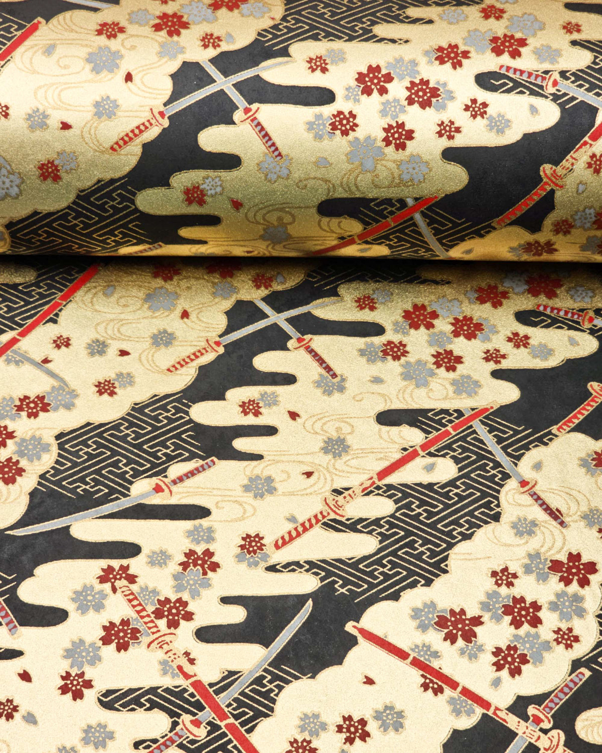 Japanese chiyogami paper featuring red and gray katana swords with gray and maroon red cherry blossoms on a black and gold background with metallic gold details, shown rolled to highlight the design.