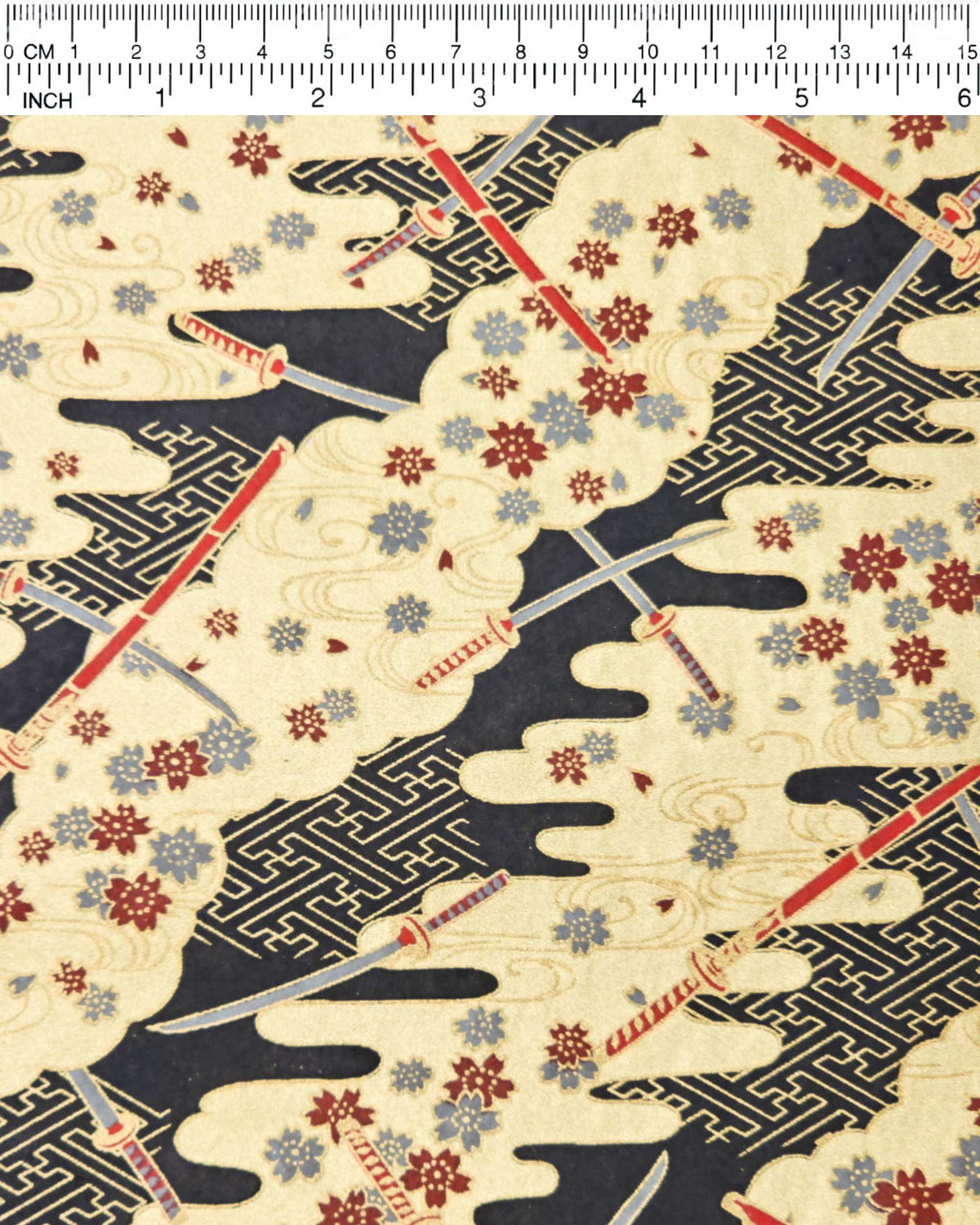 Japanese chiyogami paper featuring red and gray katana swords with gray and maroon red cherry blossoms on a black and gold background with metallic gold details, shown next to a ruler for size reference.
