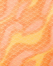 Japanese chiyogami paper featuring a large metallic gold traditional seigaiha (wave crest) pattern on a flowing background in various shades of orange. 