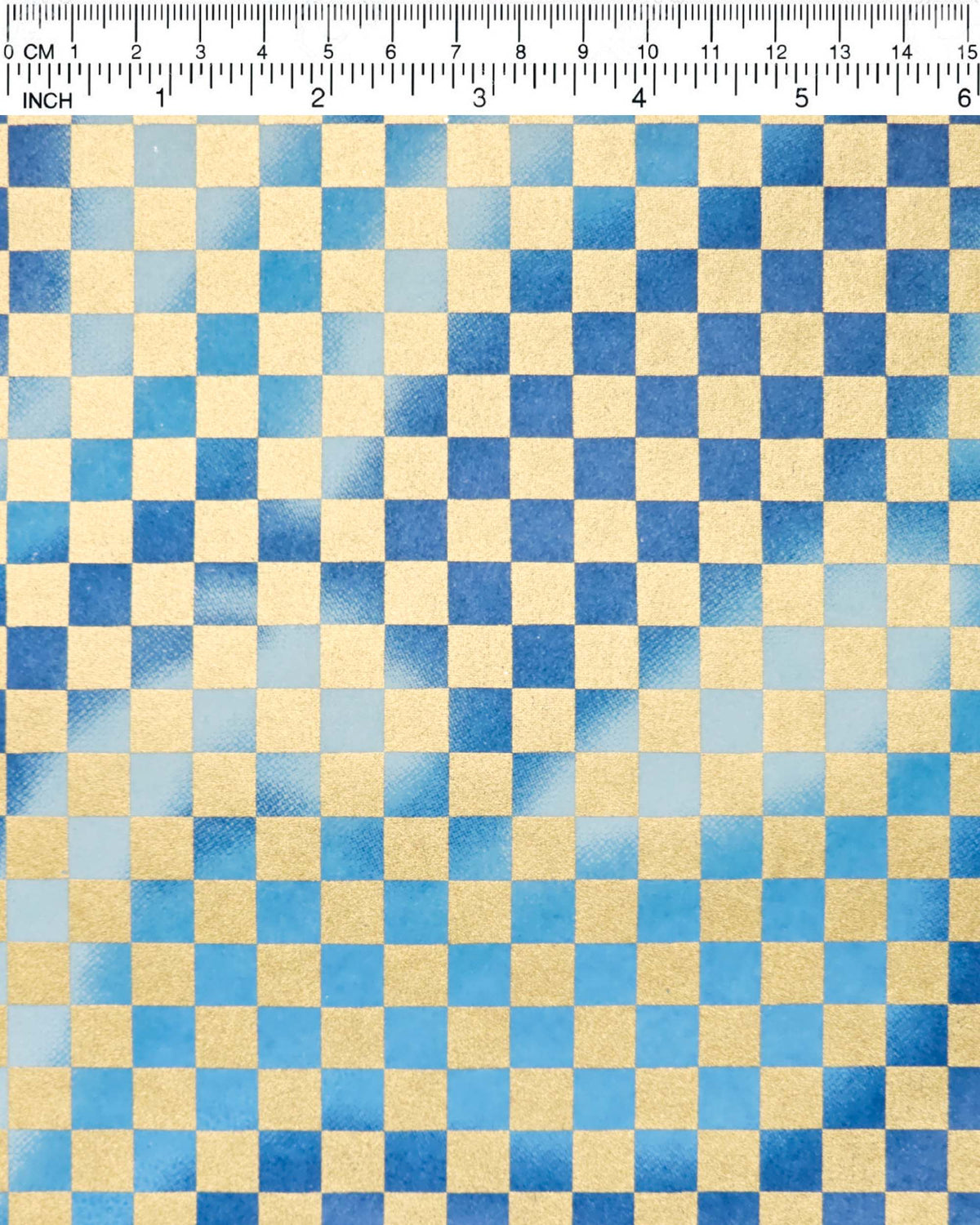 Japanese chiyogami paper featuring a large metallic gold traditional ichimatsu (checker) pattern on a flowing background in various shades of blue, shown next to a ruler for size reference.