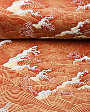 Japanese chiyogami paper featuring metallic gold waves with beige and white detailed waves on a red background, shown rolled to highlight the design.