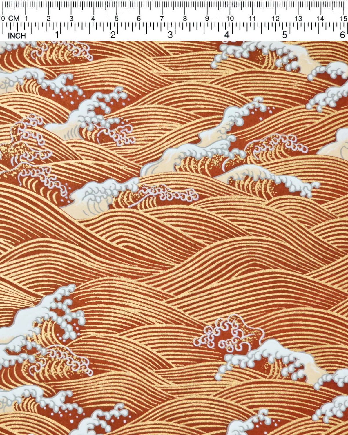 Japanese chiyogami paper featuring metallic gold waves with beige and white detailed waves on a red background, shown next to a ruler for size reference.