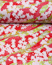 Japanese chiyogami paper featuring pink plum and cherry blossoms with flowing green ribbons on a red and silver seigaihai background with metallic gold details.