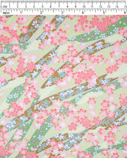 Japanese chiyogami paper featuring pink plum and cherry blossoms with flowing green and brown ribbons on a light green background with metallic gold details.