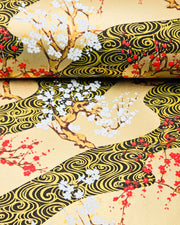 Japanese chiyogami paper featuring red and white plum and cherry blossom trees set against a metallic gold and black water ripple pattern on a gold background, shown rolled to highlight the design.
