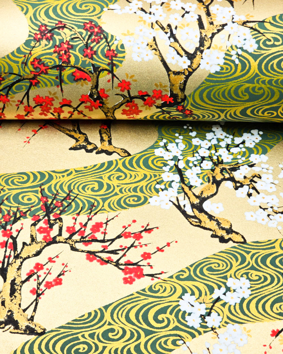 Japanese chiyogami paper featuring red and white plum and cherry blossom trees set against a metallic gold and green water ripple pattern on a gold background, shown rolled to highlight the design.