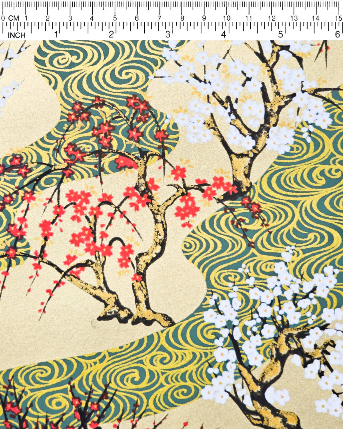 Japanese chiyogami paper featuring red and white plum and cherry blossom trees set against a metallic gold and green water ripple pattern on a gold background, shown next to a ruler for size reference.