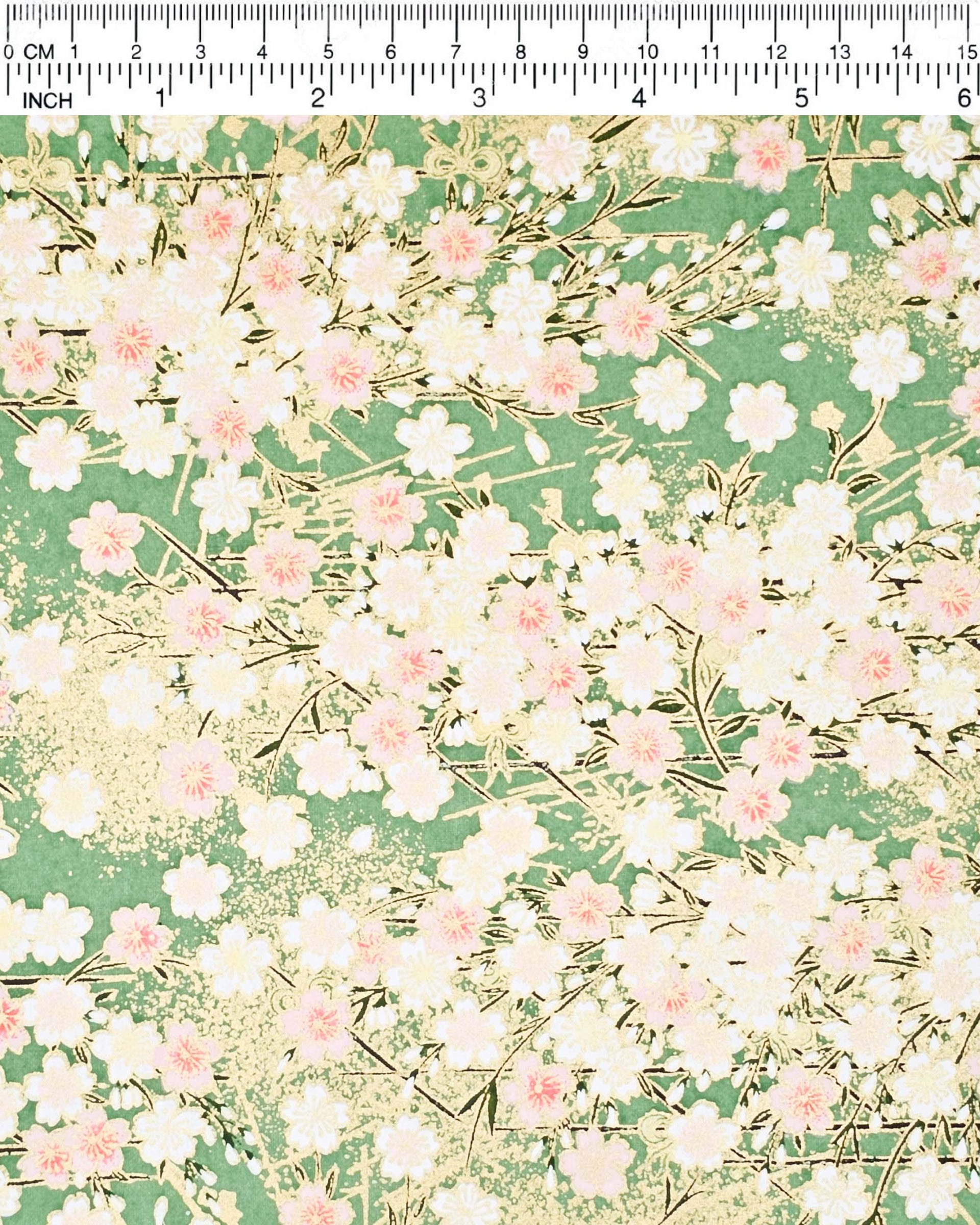 Japanese chiyogami paper featuring light pink and white cherry blossoms on a green background with metallic gold details.