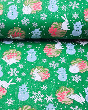 Japanese chiyogami paper featuring light blue snowmen, white rabbits, silver snowflakes, and brown yukiwas with red berries inside on a glitter green background.