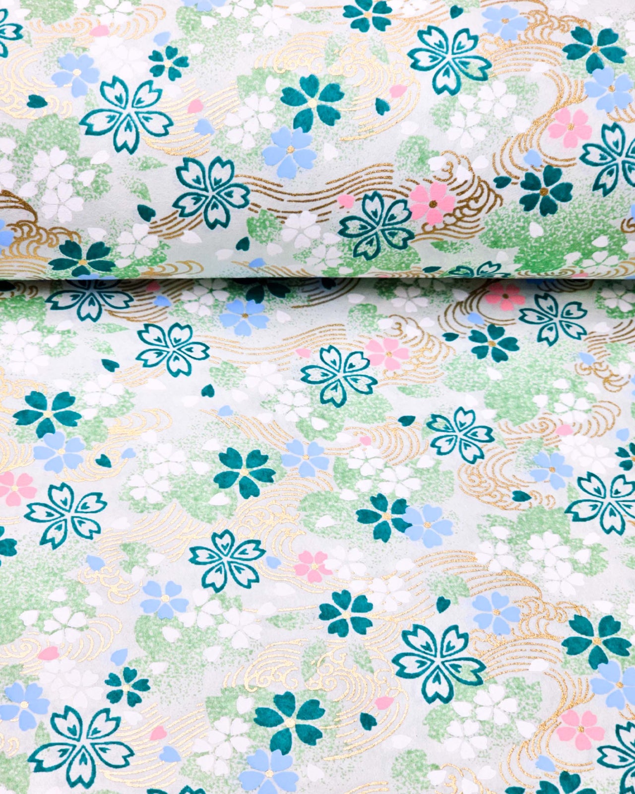 Japanese chiyogami paper featuring green, white, blue, and pink cherry blossoms on a green background with metallic gold details.