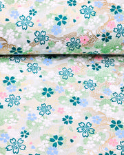 Japanese chiyogami paper featuring green, white, blue, and pink cherry blossoms on a green background with metallic gold details.