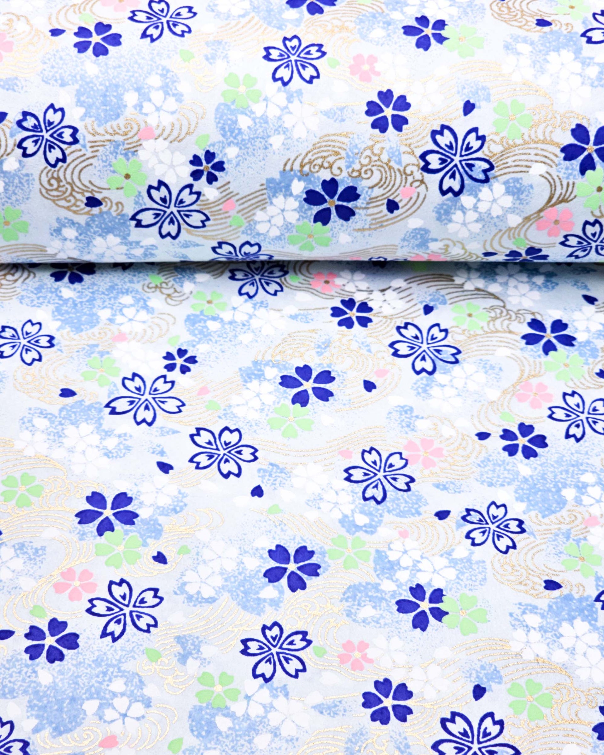Japanese chiyogami paper featuring blue, white, green, and pink cherry blossoms on a light blue background with metallic gold details.