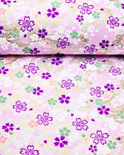Japanese chiyogami paper featuring purple, white, green, and pink cherry blossoms on a purple background with metallic gold details.